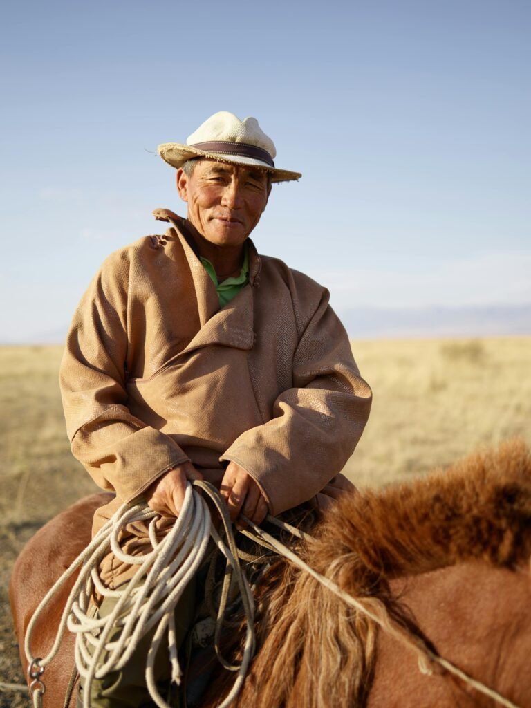 Elderly Mongolian horseman rides through the tranquil steppe.